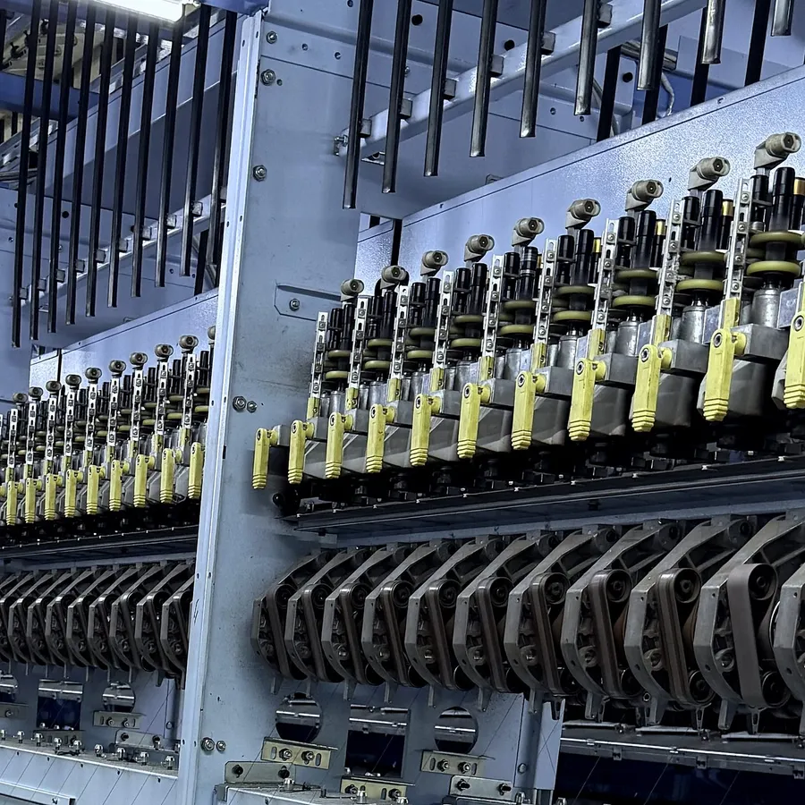 Rows of yellow yarn guides and spindles on a texturing machine, close up